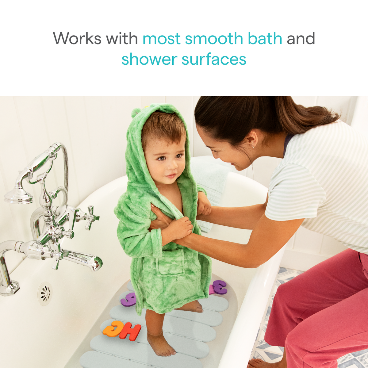 Toddler in green hooded robe stands on a gray non-slip bath mat while a woman helps; text reads "Works with most smooth bath and shower surfaces"