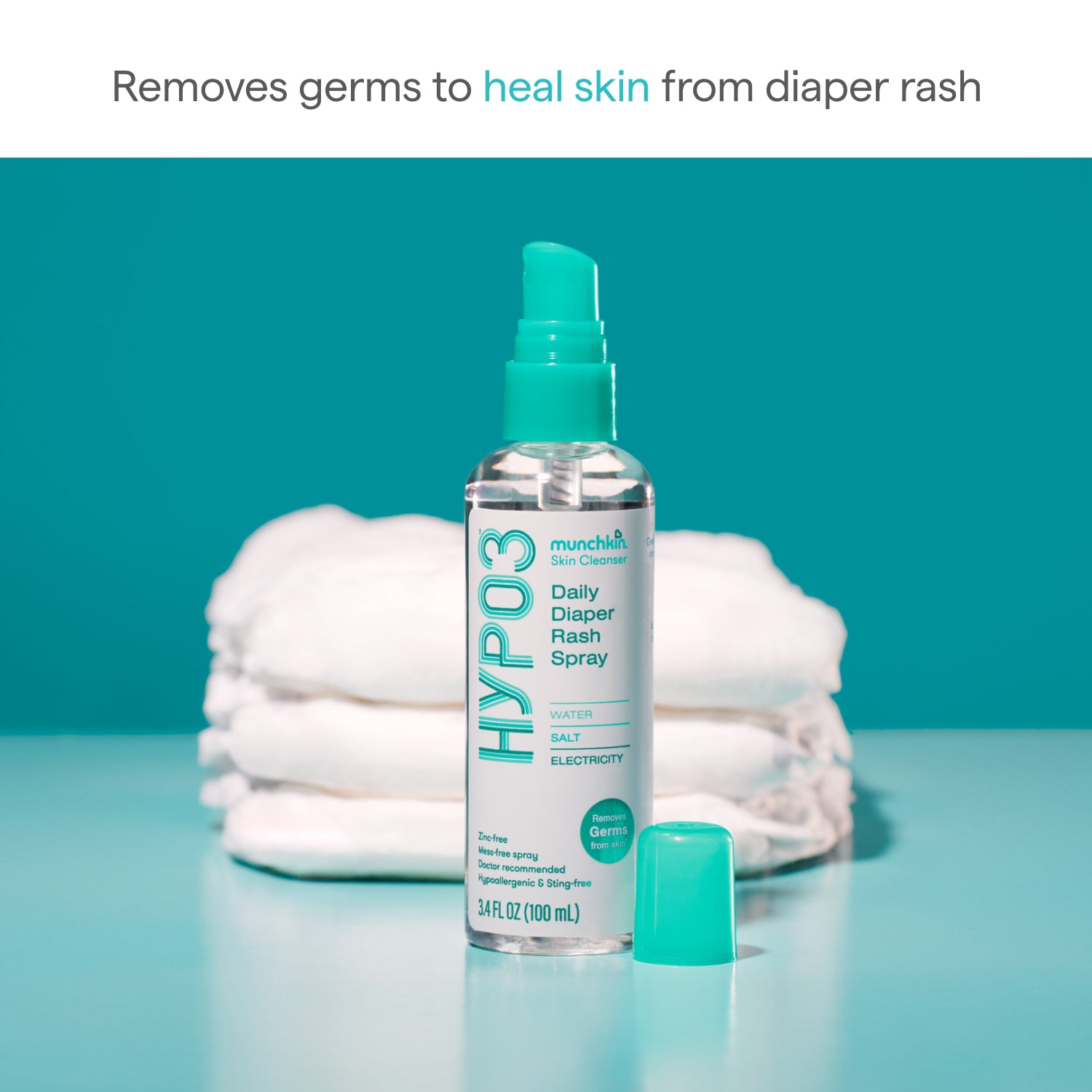 Munchkin HYPO3 Daily Diaper Rash Spray with a stack of diapers on a teal background